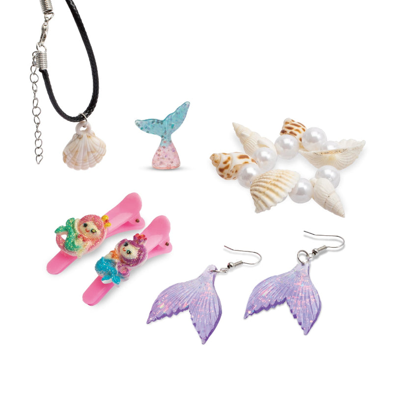 A collection of completed mermaid-themed accessories including a black cord shell necklace, a clear blue mermaid tail charm, a shell and pearl beaded bracelet, two pink mermaid hair clips, and a pair of iridescent purple mermaid tail earrings.