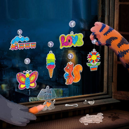 Colorful window stickers being applied to a dark window with a hand using a tool.