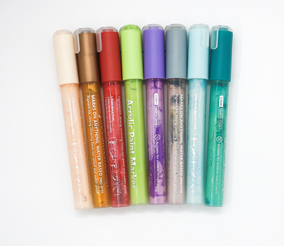 Set of acrylic paint markers in various colors on a white background