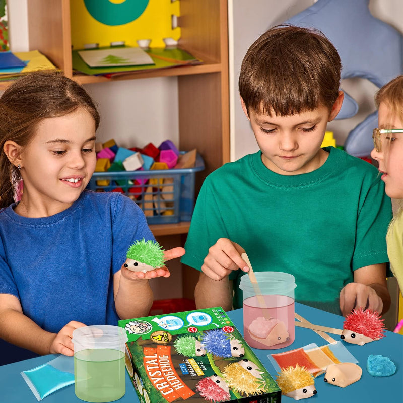 Three children sitting around a table stirring crystal powder solution in clear containers to grow their colourful crystal hedgehog figures.