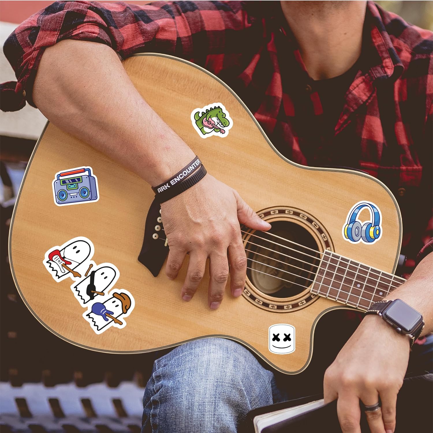 Person holding a guitar with various stickers on the body