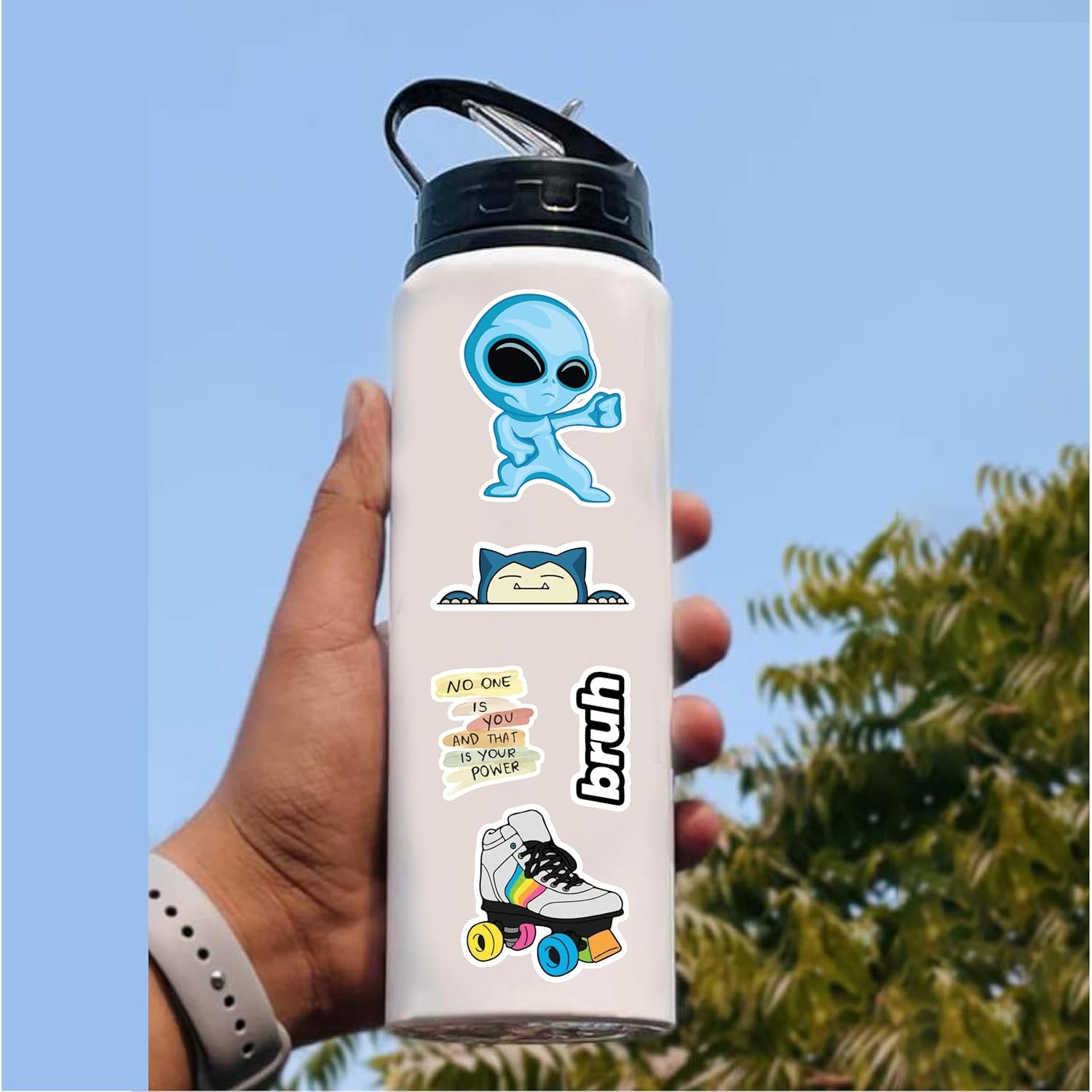 White water bottle with colorful designs held by a hand against a blue sky and tree background