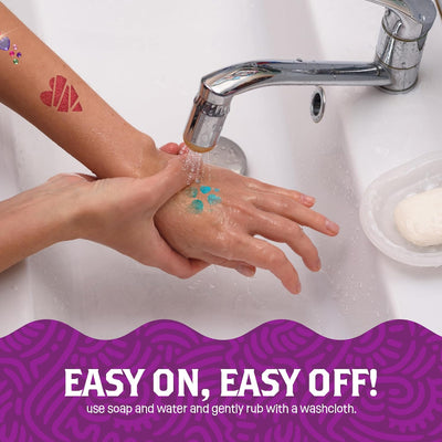 Person washing glitter body tattoos off their hand under running tap water using soap.