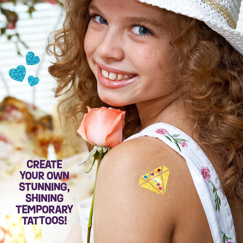 Young girl smiling while showing a large yellow diamond-shaped temporary tattoo adorned with colorful stick-on gems on her shoulder.